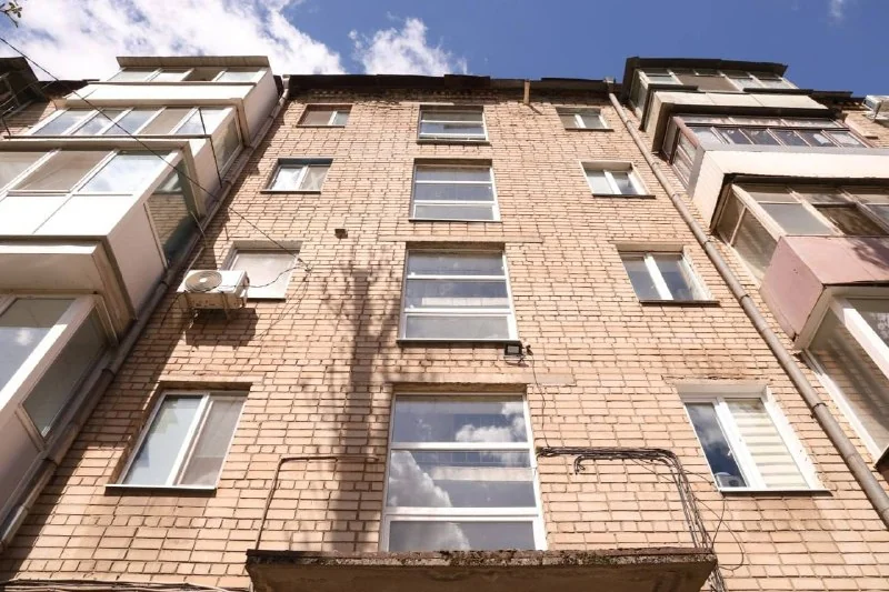 Цегляна багатоповерхівка з балконами, вікнами та кондиціонером під небом