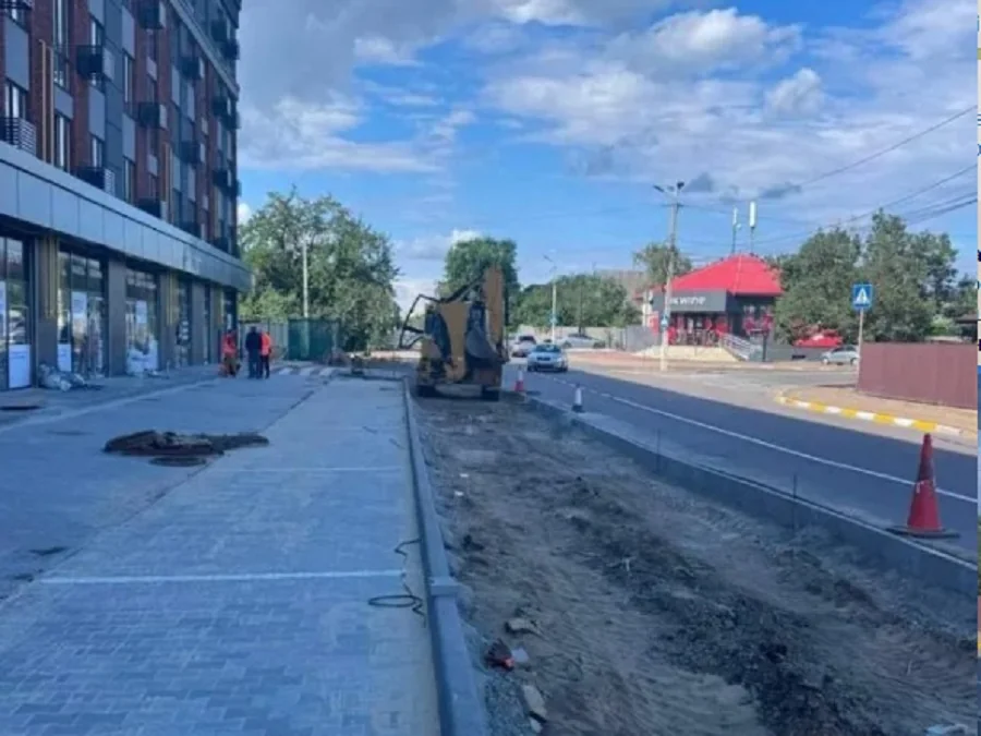 Новий тротуар, розрита смуга та екскаватор біля багатоповерхівки на вулиці