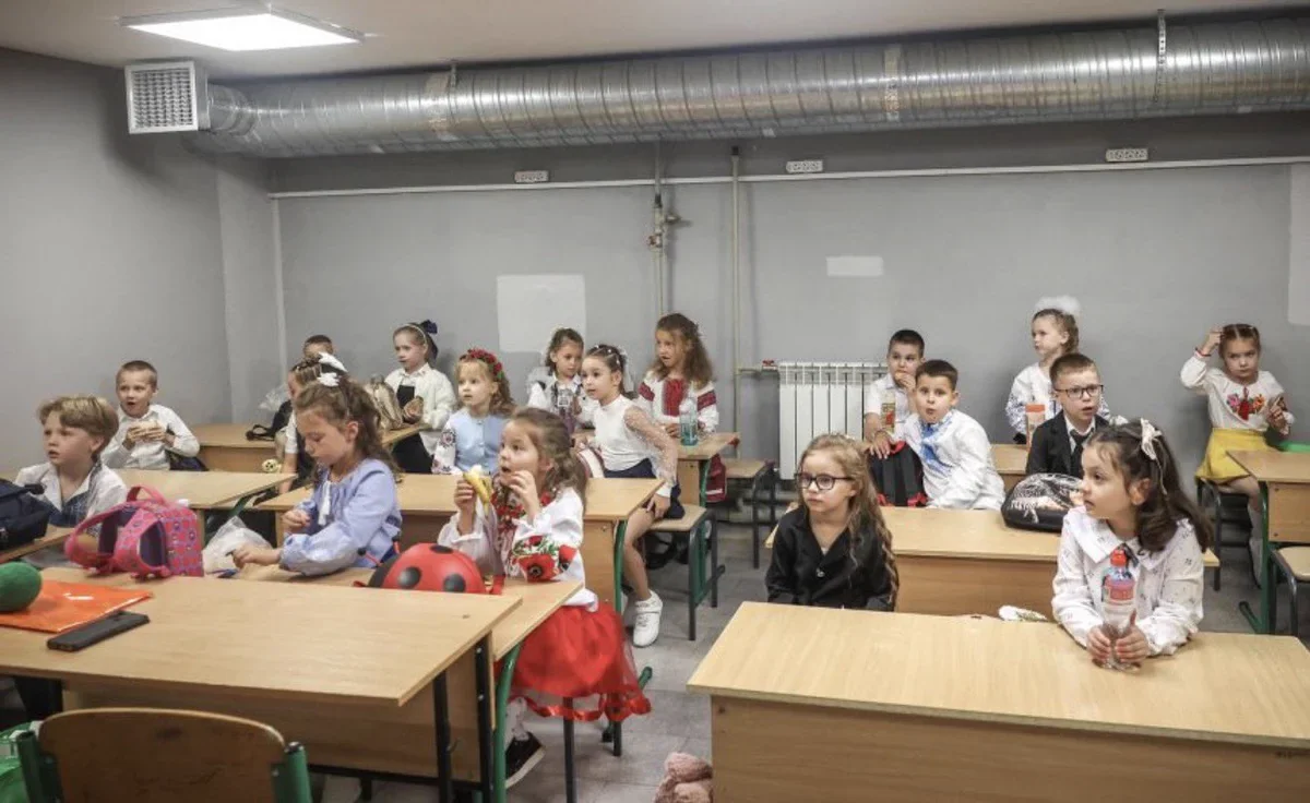 Діти сидять за партами в класі під час уроку в укритті школи